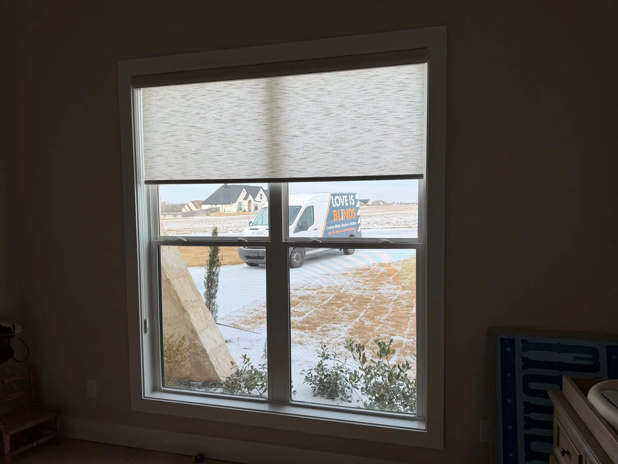 Blackout roller shade lowered for full darkness in a bedroom
